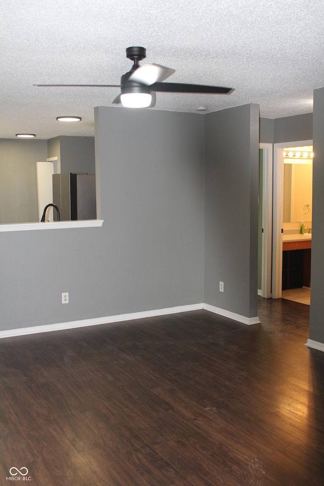 empty room with a textured ceiling, dark wood-type flooring, and ceiling fan