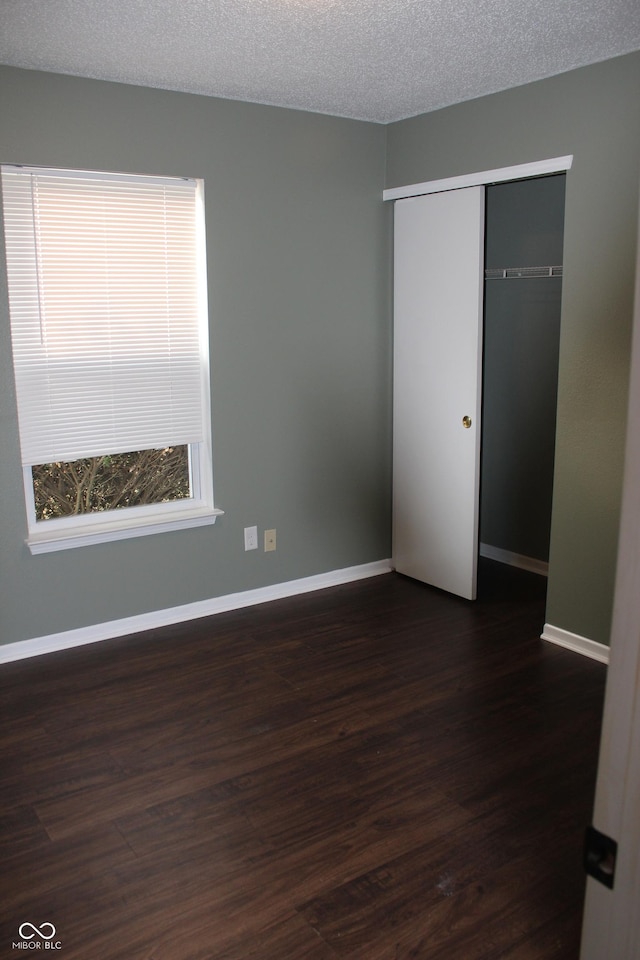 empty room featuring a textured ceiling and dark hardwood / wood-style floors