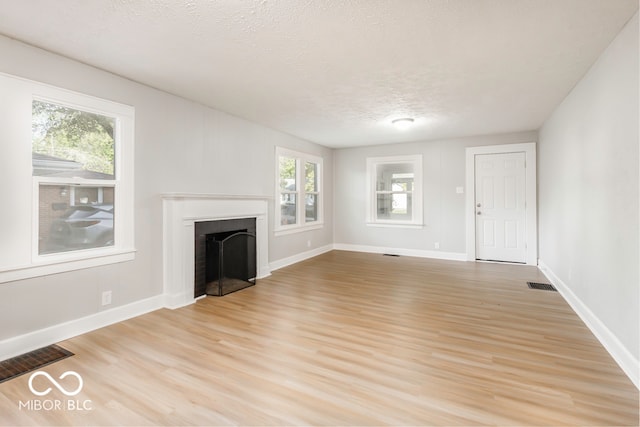 unfurnished living room featuring light wood-type flooring and a textured ceiling