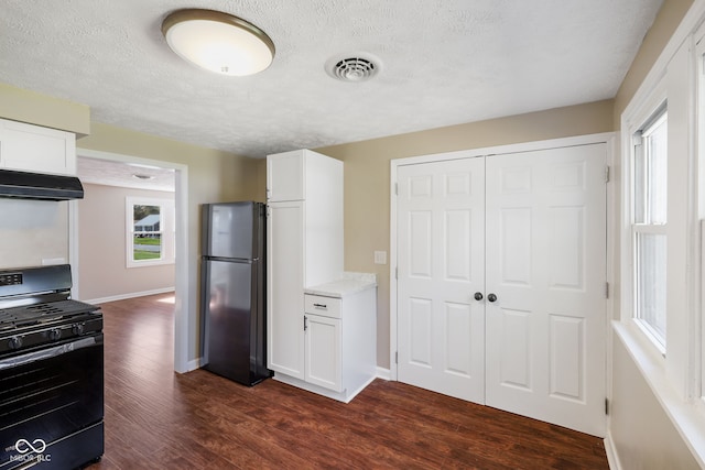 kitchen with white cabinets, gas stove, dark wood-type flooring, stainless steel refrigerator, and a textured ceiling