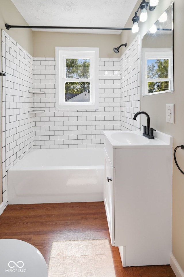 bathroom with tiled shower / bath, vanity, a textured ceiling, and hardwood / wood-style flooring