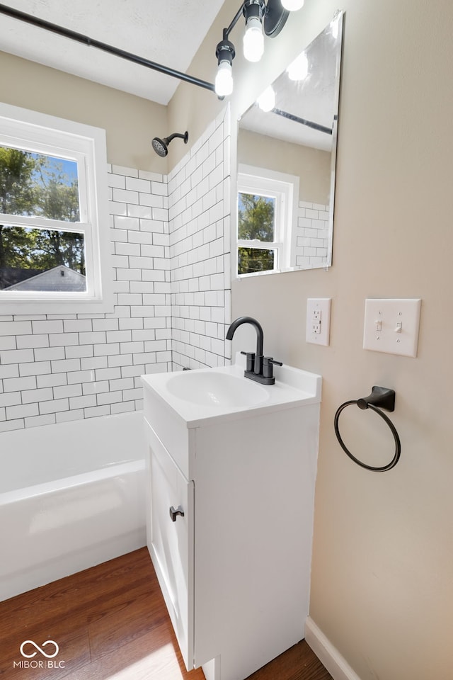 bathroom featuring hardwood / wood-style flooring, vanity, and tiled shower / bath combo