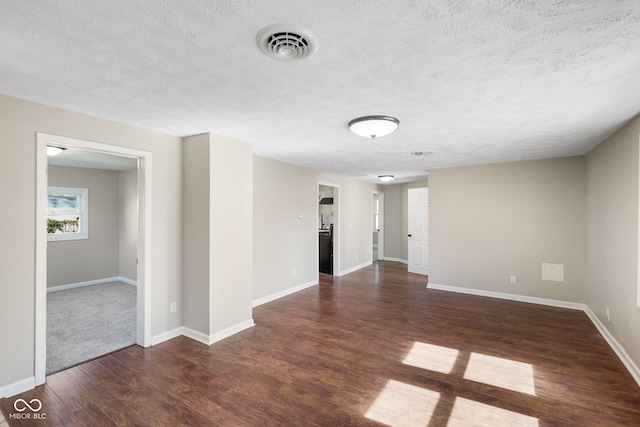 spare room featuring dark wood-type flooring and a textured ceiling