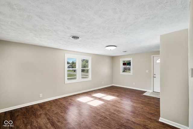 unfurnished room with a textured ceiling and dark hardwood / wood-style flooring