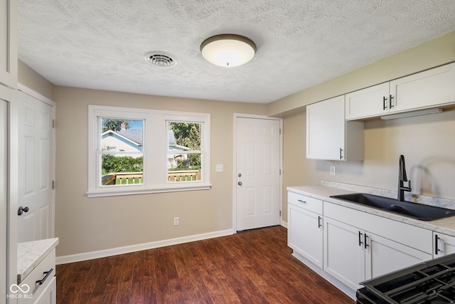 kitchen featuring sink, a textured ceiling, white cabinetry, light stone countertops, and dark hardwood / wood-style flooring