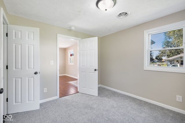 unfurnished bedroom featuring light carpet and a textured ceiling