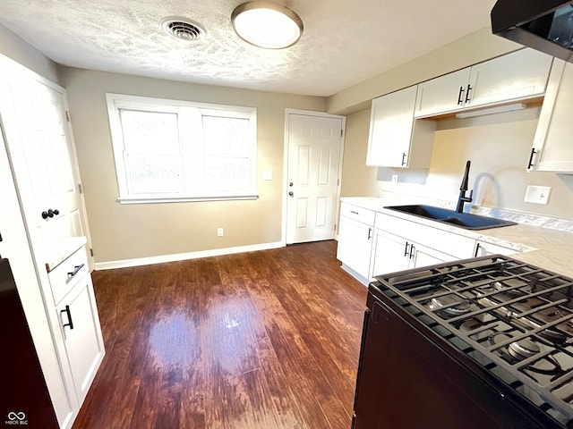 kitchen with sink, black range, dark hardwood / wood-style flooring, white cabinetry, and a textured ceiling