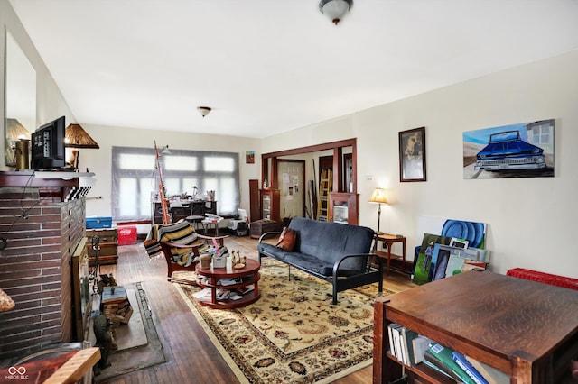 living room with hardwood / wood-style floors and a brick fireplace