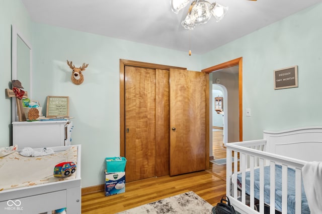 bedroom featuring a crib, light wood-type flooring, and a closet