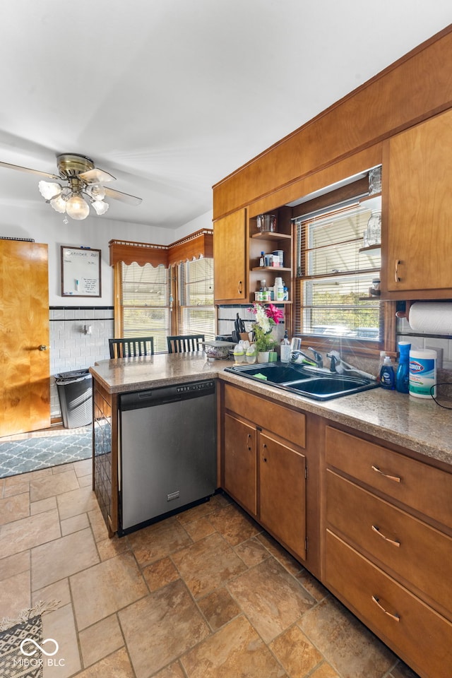 kitchen with stainless steel dishwasher, a sink, stone tile flooring, and plenty of natural light
