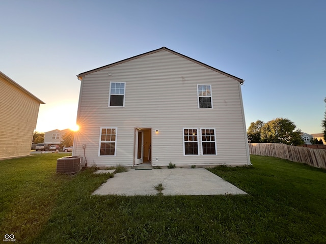 back house at dusk with a patio and a yard