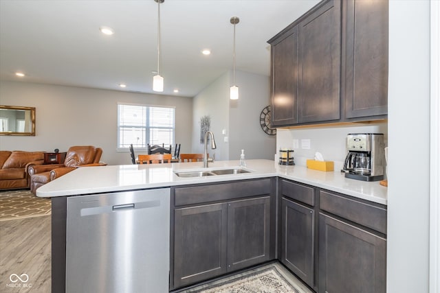 kitchen with light hardwood / wood-style flooring, sink, dishwasher, kitchen peninsula, and hanging light fixtures