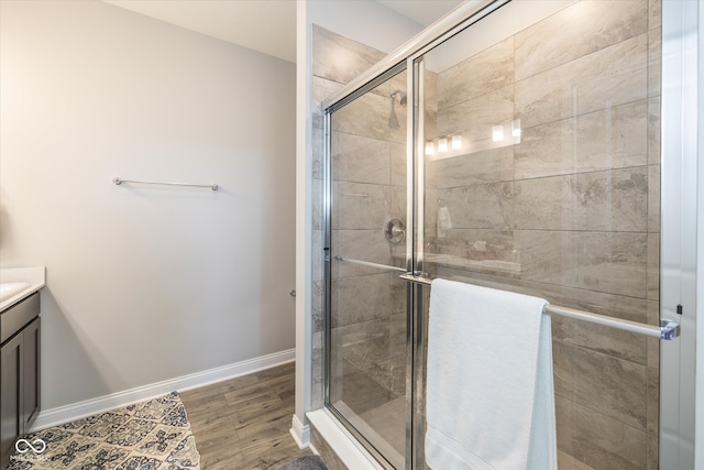 bathroom with a shower with door, hardwood / wood-style floors, and vanity