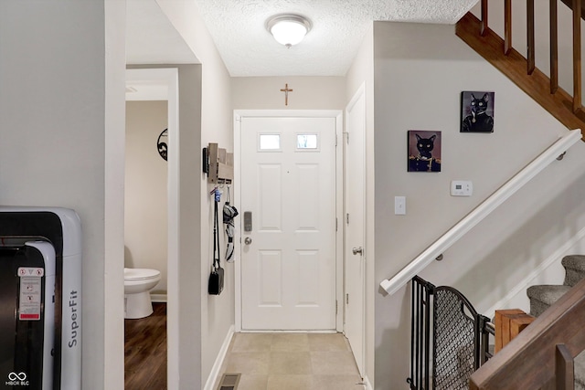 foyer entrance featuring a textured ceiling and light hardwood / wood-style flooring