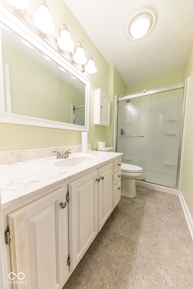 bathroom featuring toilet, a shower with door, vanity, and a textured ceiling