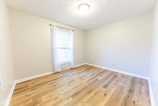 unfurnished room with a textured ceiling and light wood-type flooring