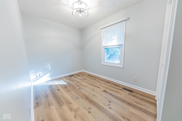 spare room featuring a textured ceiling and light hardwood / wood-style flooring