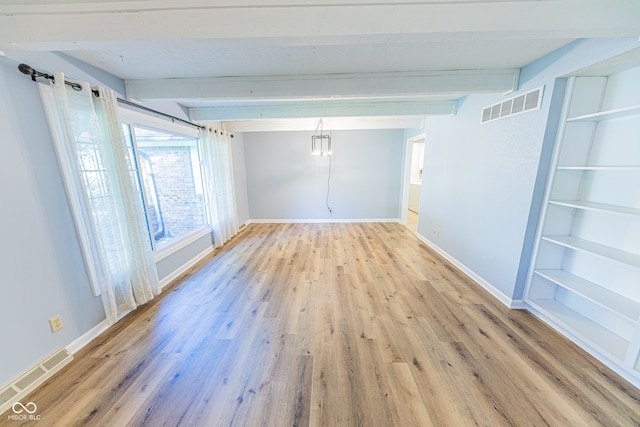 empty room featuring beamed ceiling and light hardwood / wood-style flooring