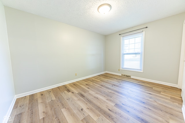 spare room featuring a textured ceiling and light wood-type flooring