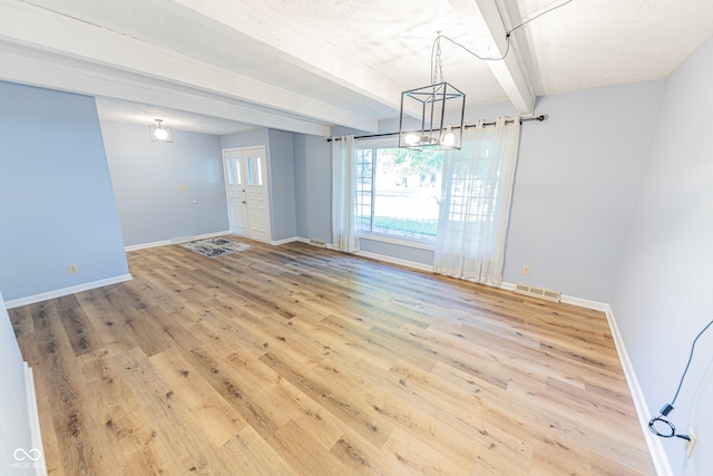 unfurnished dining area featuring wood-type flooring, beamed ceiling, and a textured ceiling