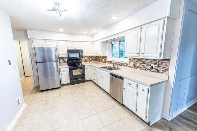 kitchen with sink, white cabinetry, decorative backsplash, and black appliances