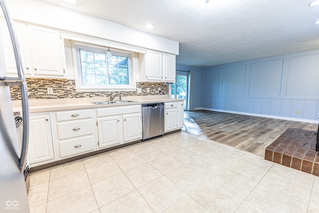 kitchen featuring light wood-type flooring, sink, stainless steel appliances, a wealth of natural light, and white cabinetry