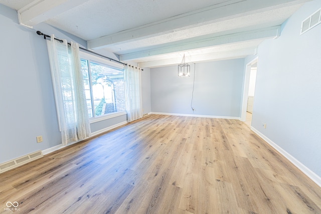 empty room featuring beamed ceiling and light wood-type flooring