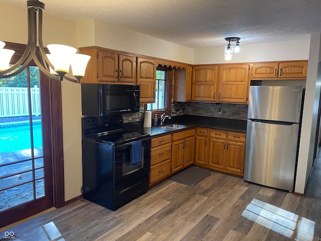 kitchen featuring sink, black appliances, an inviting chandelier, dark hardwood / wood-style flooring, and decorative backsplash