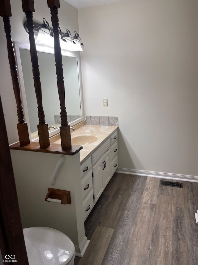 bathroom with toilet, vanity, and wood-type flooring