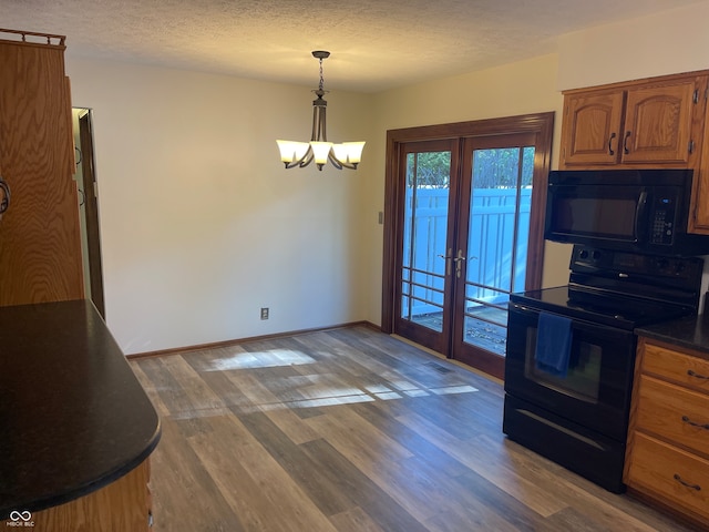 kitchen featuring wood-type flooring, a textured ceiling, decorative light fixtures, a chandelier, and black appliances