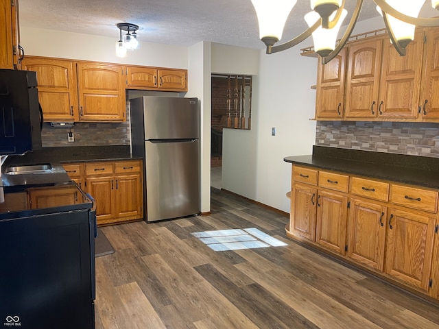 kitchen with stainless steel fridge, tasteful backsplash, a notable chandelier, sink, and dark hardwood / wood-style floors