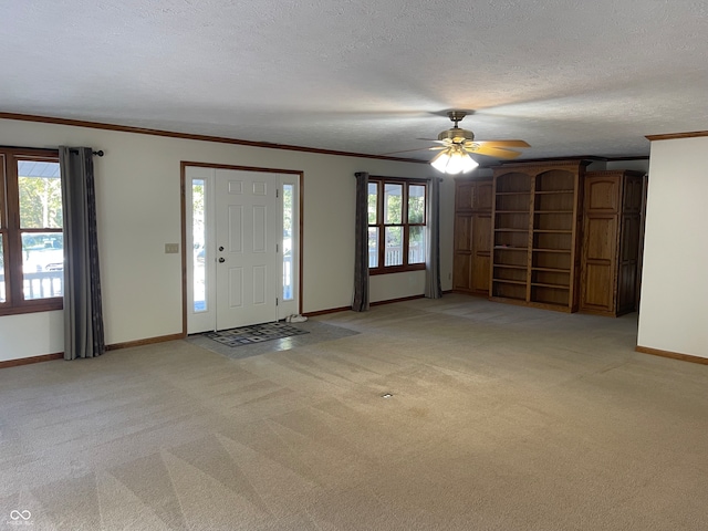 entrance foyer with light colored carpet, a textured ceiling, and a healthy amount of sunlight