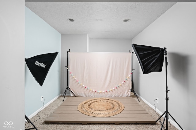 miscellaneous room featuring light colored carpet and a textured ceiling