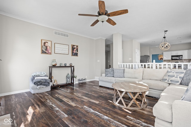 living room with ceiling fan with notable chandelier, dark hardwood / wood-style floors, and crown molding