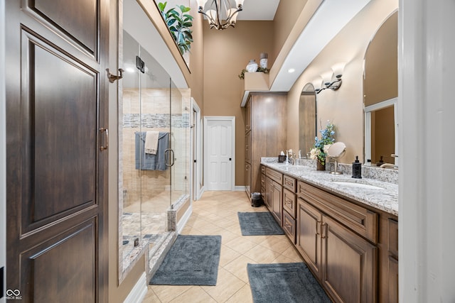 bathroom with a shower with door, an inviting chandelier, a high ceiling, vanity, and tile patterned flooring