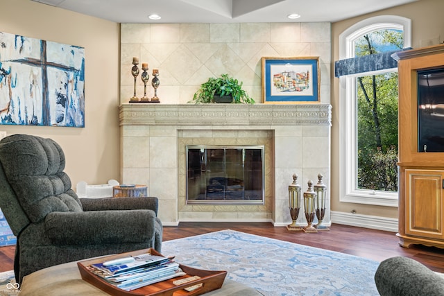 living room with tile walls, a tile fireplace, and dark hardwood / wood-style flooring