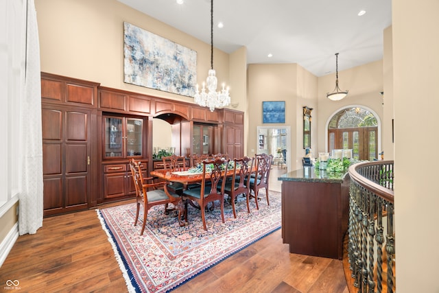 dining room with a notable chandelier, high vaulted ceiling, and dark wood-type flooring