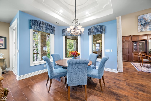 dining space featuring an inviting chandelier, dark hardwood / wood-style floors, and a raised ceiling