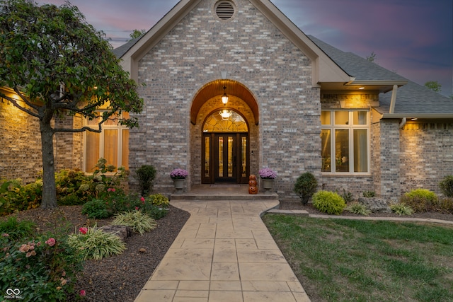 exterior entry at dusk with french doors and a lawn