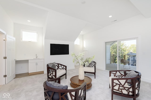 living area featuring light colored carpet, sink, and vaulted ceiling