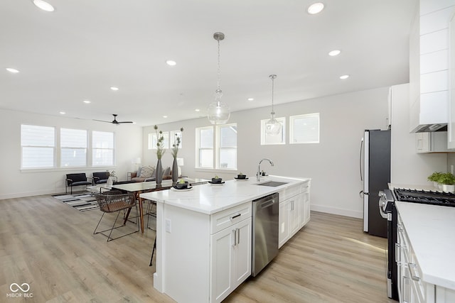 kitchen featuring a kitchen island with sink, sink, light hardwood / wood-style flooring, appliances with stainless steel finishes, and white cabinetry