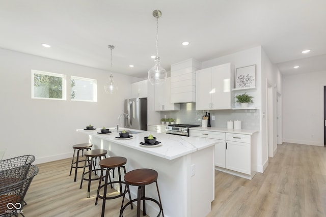 kitchen with white cabinetry, a center island with sink, and stainless steel appliances