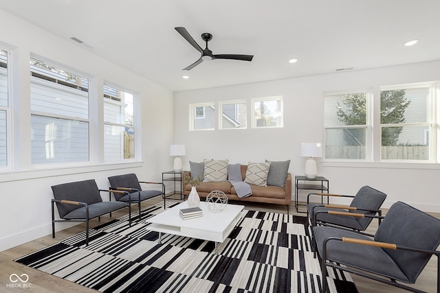 living room featuring light hardwood / wood-style flooring, ceiling fan, and a healthy amount of sunlight