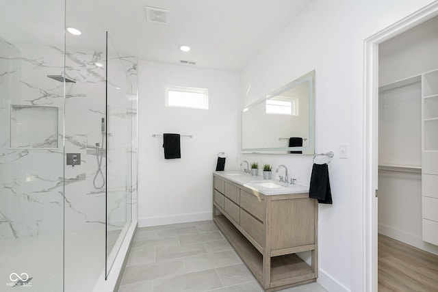 bathroom with hardwood / wood-style flooring, vanity, and tiled shower