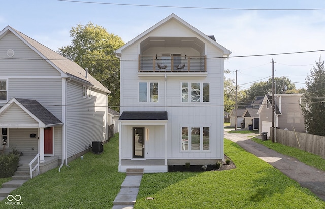 view of front of property with central air condition unit, a balcony, and a front lawn