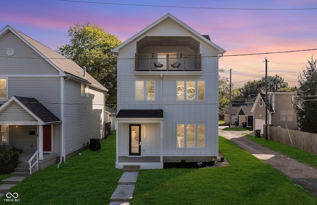 view of front of home with a yard, a balcony, and central AC unit