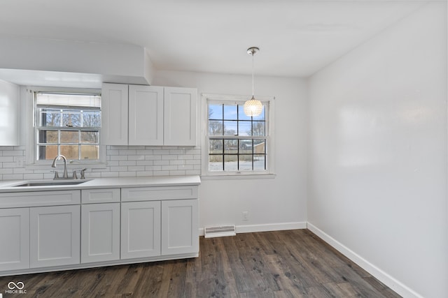 kitchen featuring decorative backsplash, sink, white cabinets, pendant lighting, and dark hardwood / wood-style flooring