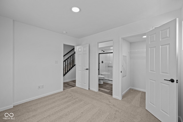 unfurnished bedroom featuring ensuite bathroom, light colored carpet, and a closet