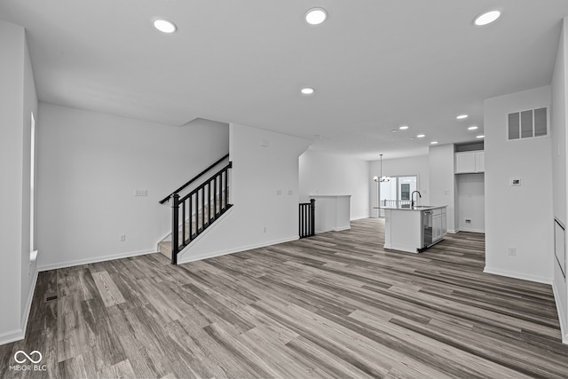 unfurnished living room with hardwood / wood-style flooring, sink, and a chandelier