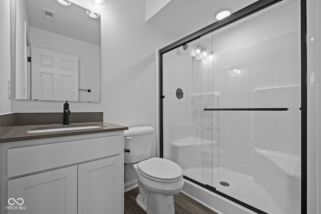 bathroom featuring vanity, wood-type flooring, an enclosed shower, and toilet